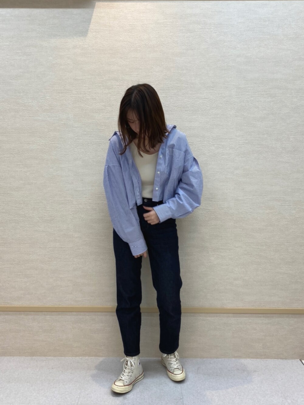 ブルー系のデニムパンツ、ホワイト系のスニーカー、ブルー系のシャツ/ブラウスを着用したレディースの春コーディネートの2枚目の写真