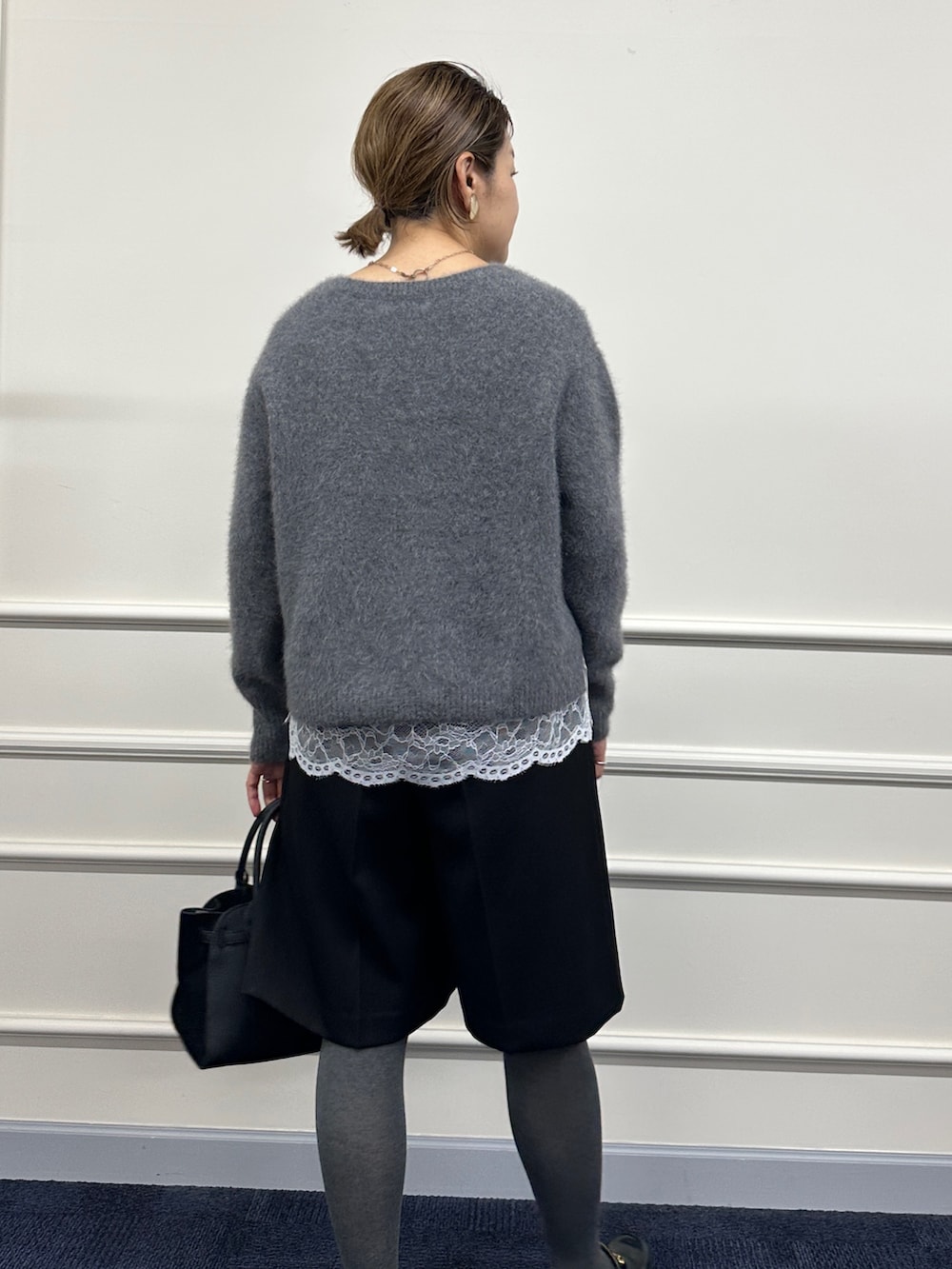 グレー系のニット/セーター、ホワイト系のシャツ/ブラウス、ブラック系のその他パンツを着用したレディースの秋コーディネートの7枚目の写真