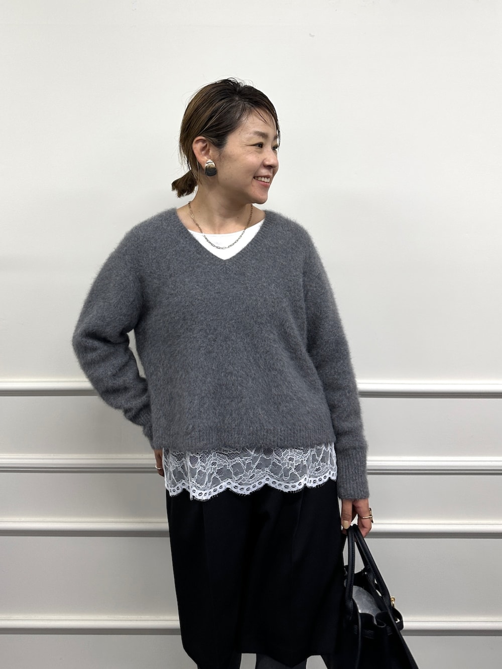 グレー系のニット/セーター、ホワイト系のシャツ/ブラウス、ブラック系のその他パンツを着用したレディースの秋コーディネートの2枚目の写真