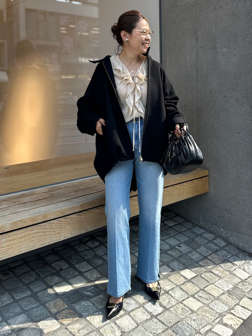 ブラック系のチェスターコート、ブルー系のデニムパンツ、ベージュ系のシャツ/ブラウスを着用したレディースの秋コーディネートの3枚目の写真
