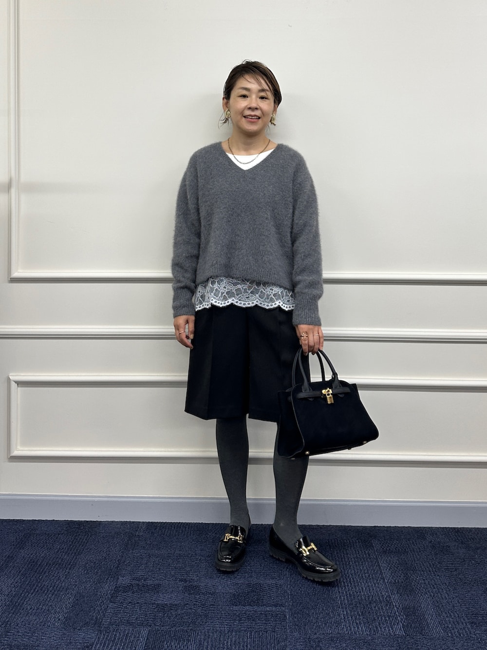 グレー系のニット/セーター、ホワイト系のシャツ/ブラウス、ブラック系のその他パンツを着用したレディースの秋コーディネートの8枚目の写真