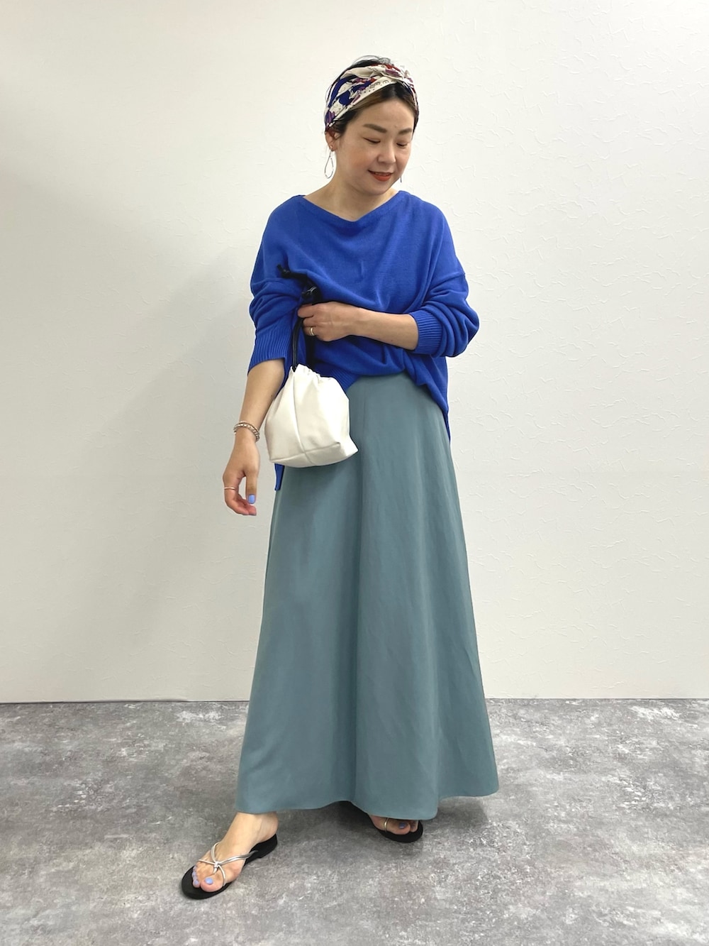 ブルー系のニット/セーター、ブルー系のスカート、ホワイト系のショルダーバッグを着用したレディースの春コーディネートの4枚目の写真