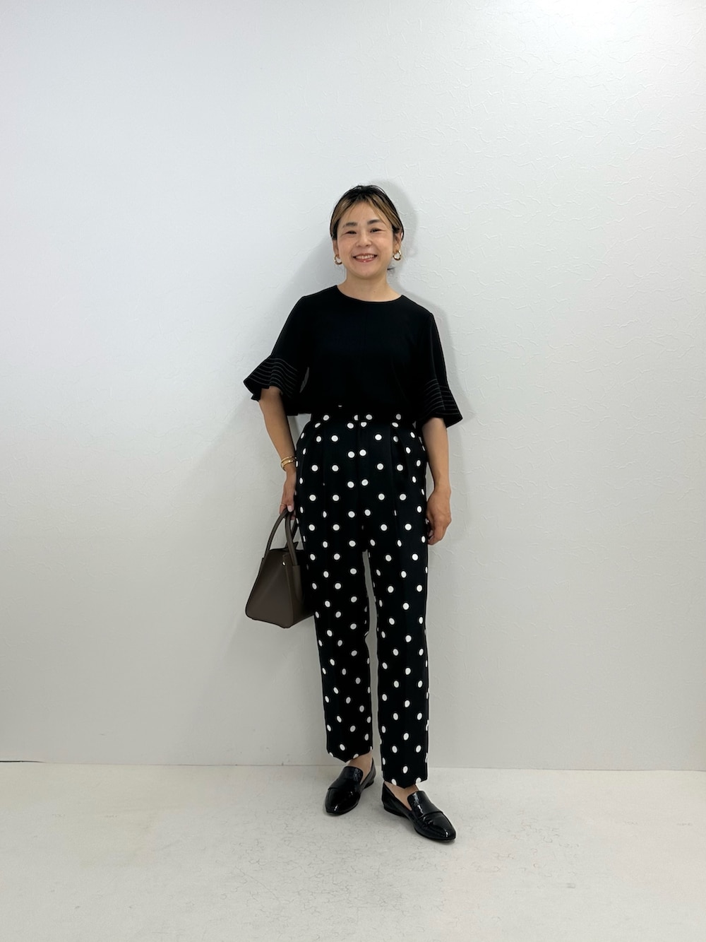 ブラック系のシャツ/ブラウス、ブラック系のその他パンツ、ベージュ系のトートバッグを着用したレディースの夏コーディネートの2枚目の写真