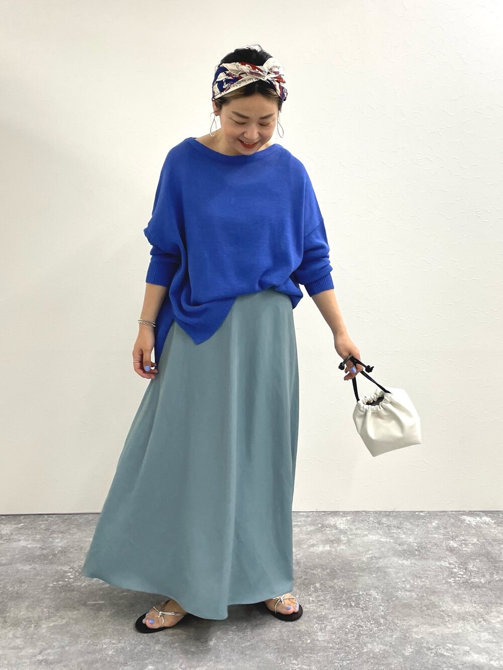 ブルー系のニット/セーター、ブルー系のスカート、ホワイト系のショルダーバッグを着用したレディースの春コーディネートの3枚目の写真