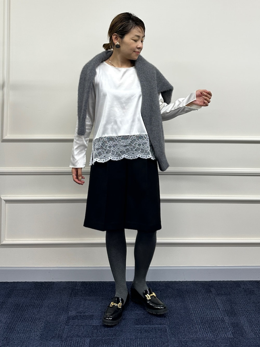 グレー系のニット/セーター、ホワイト系のシャツ/ブラウス、ブラック系のその他パンツを着用したレディースの秋コーディネートの3枚目の写真