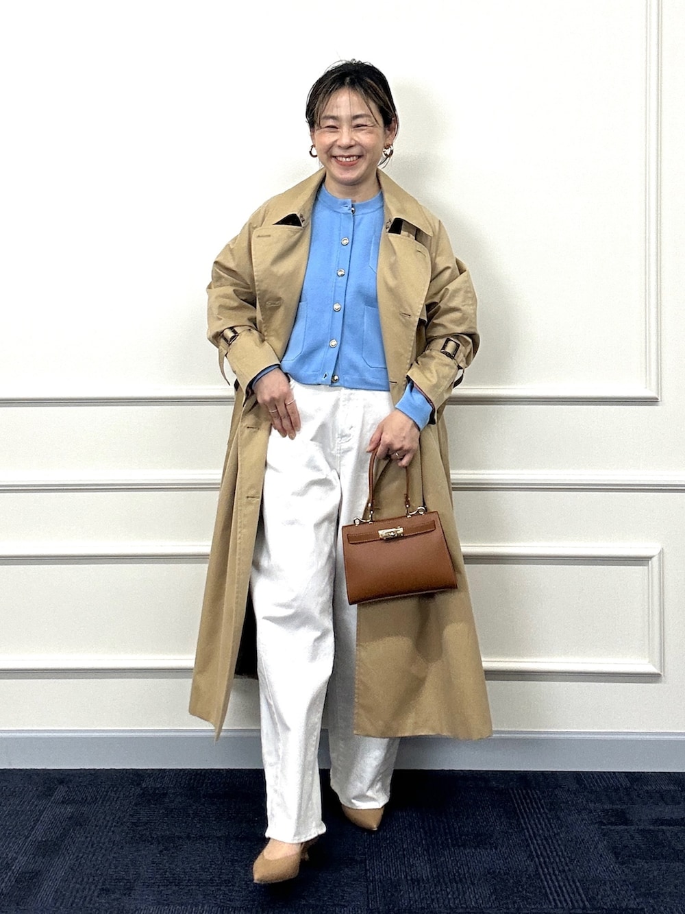 ベージュ系のトレンチコート、ブルー系のカーディガン/ボレロ、イエロー系のショルダーバッグを着用したレディースの春コーディネートの2枚目の写真