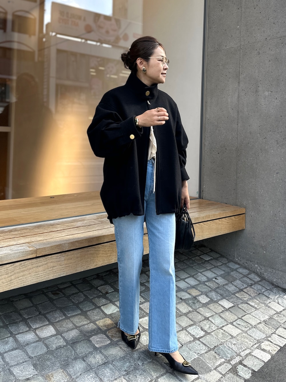 ブラック系のチェスターコート、ブルー系のデニムパンツ、ベージュ系のシャツ/ブラウスを着用したレディースの秋コーディネートの6枚目の写真