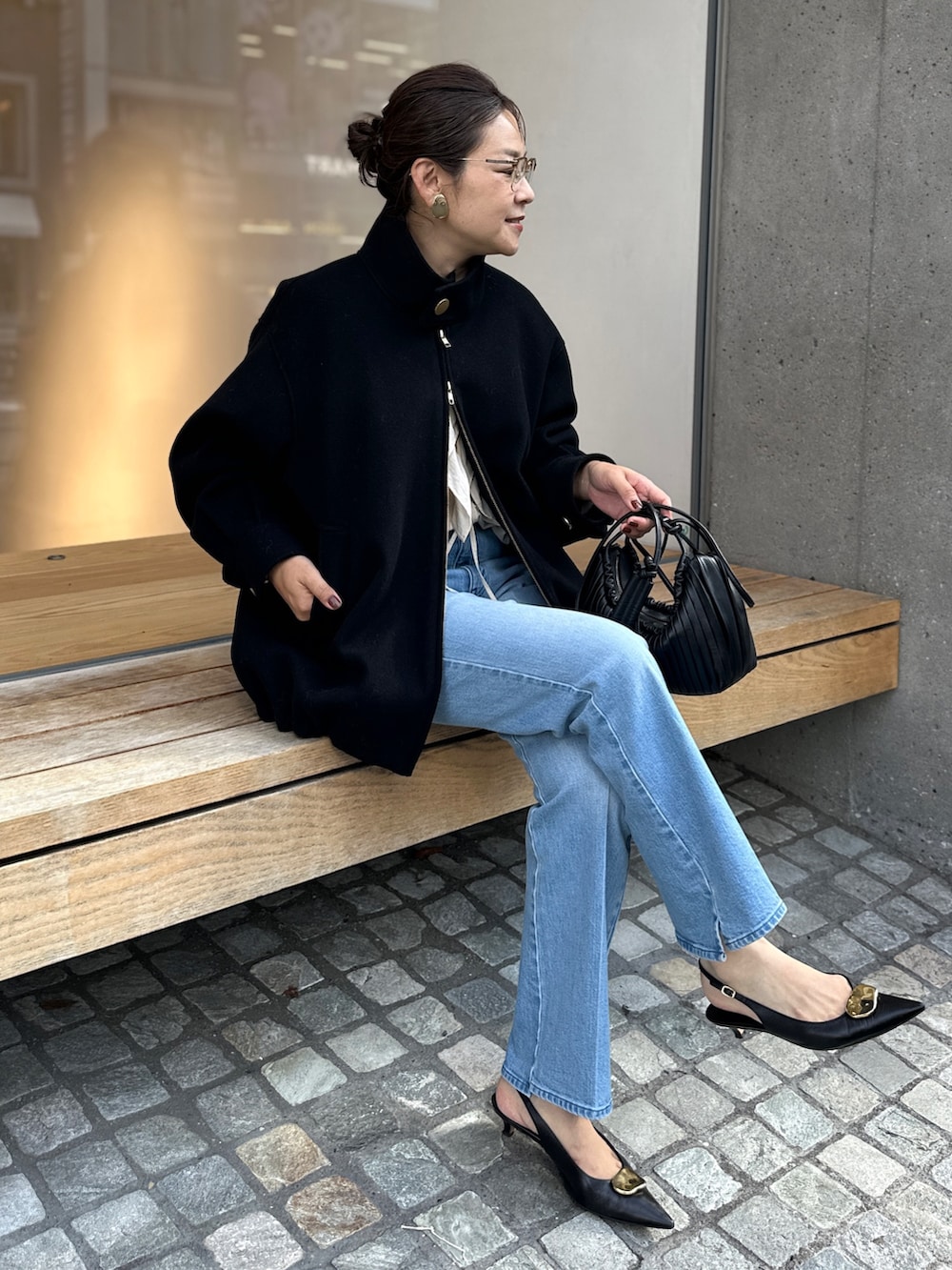 ブラック系のチェスターコート、ブルー系のデニムパンツ、ベージュ系のシャツ/ブラウスを着用したレディースの秋コーディネートの7枚目の写真
