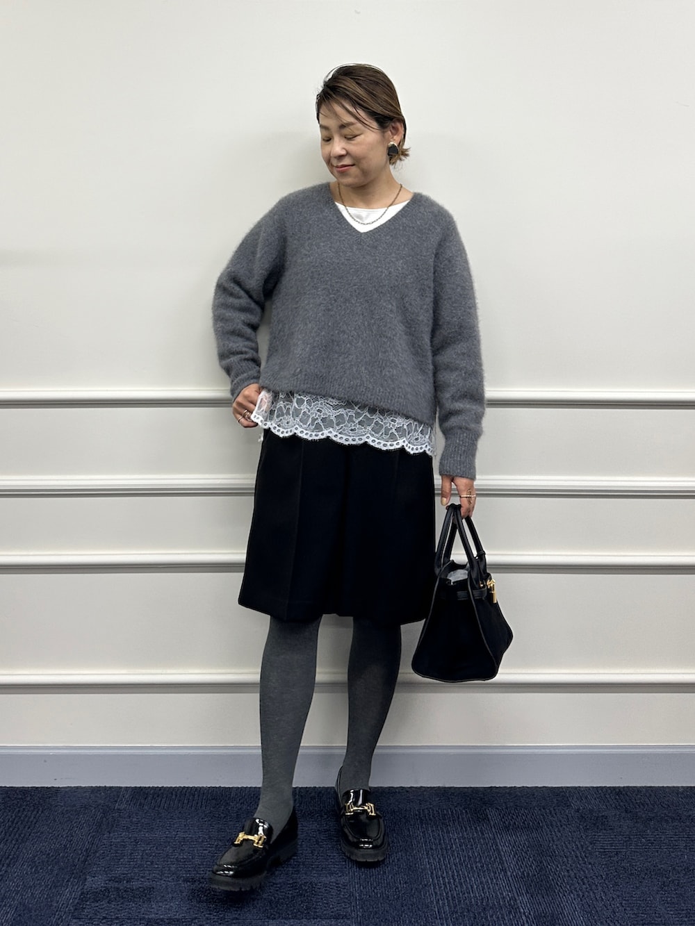 グレー系のニット/セーター、ホワイト系のシャツ/ブラウス、ブラック系のその他パンツを着用したレディースの秋コーディネートの5枚目の写真