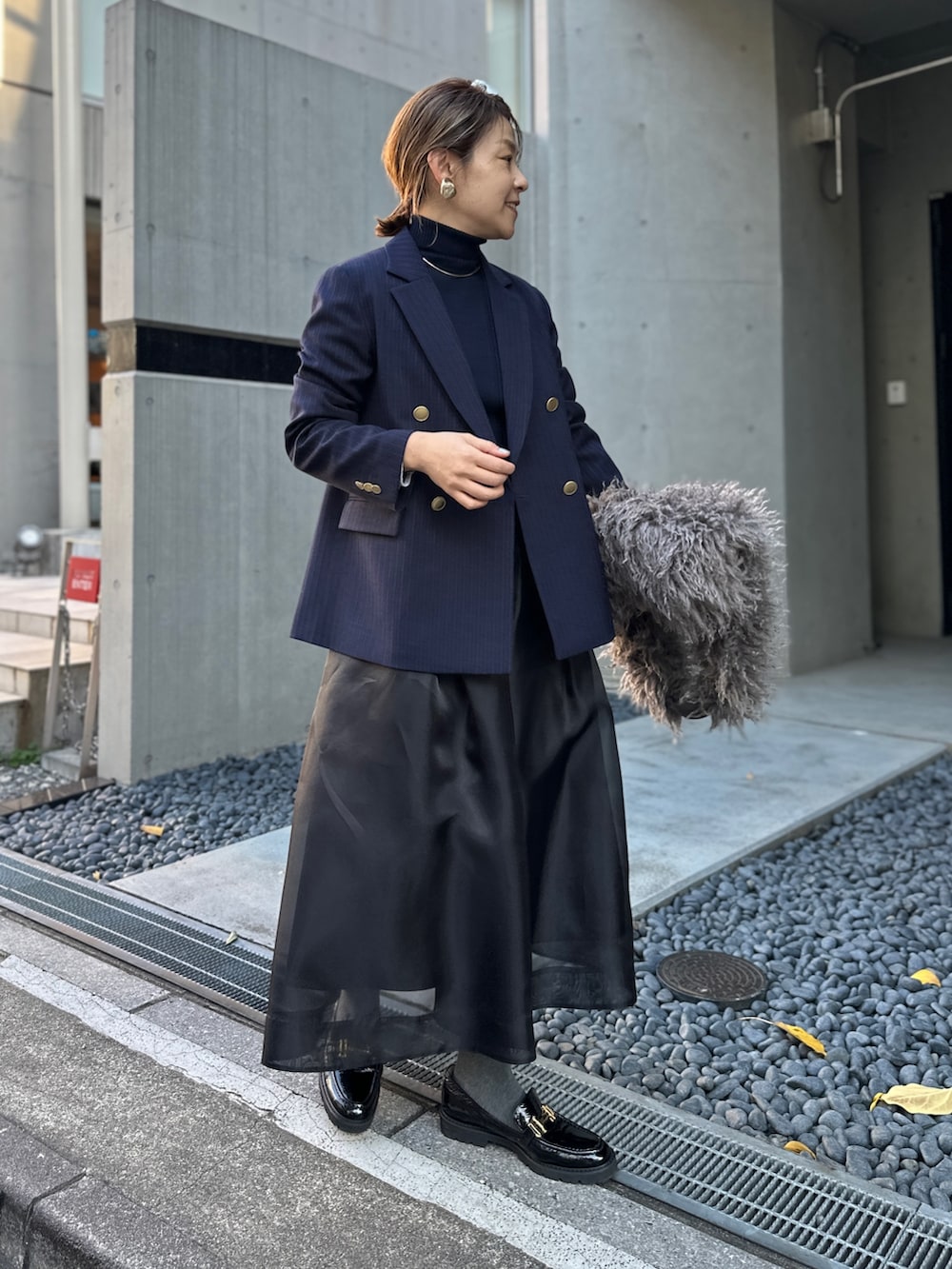 ブラック系のスカート、ブルー系のその他トップス、ブルー系のテーラードジャケットを着用したレディースの冬コーディネートの3枚目の写真