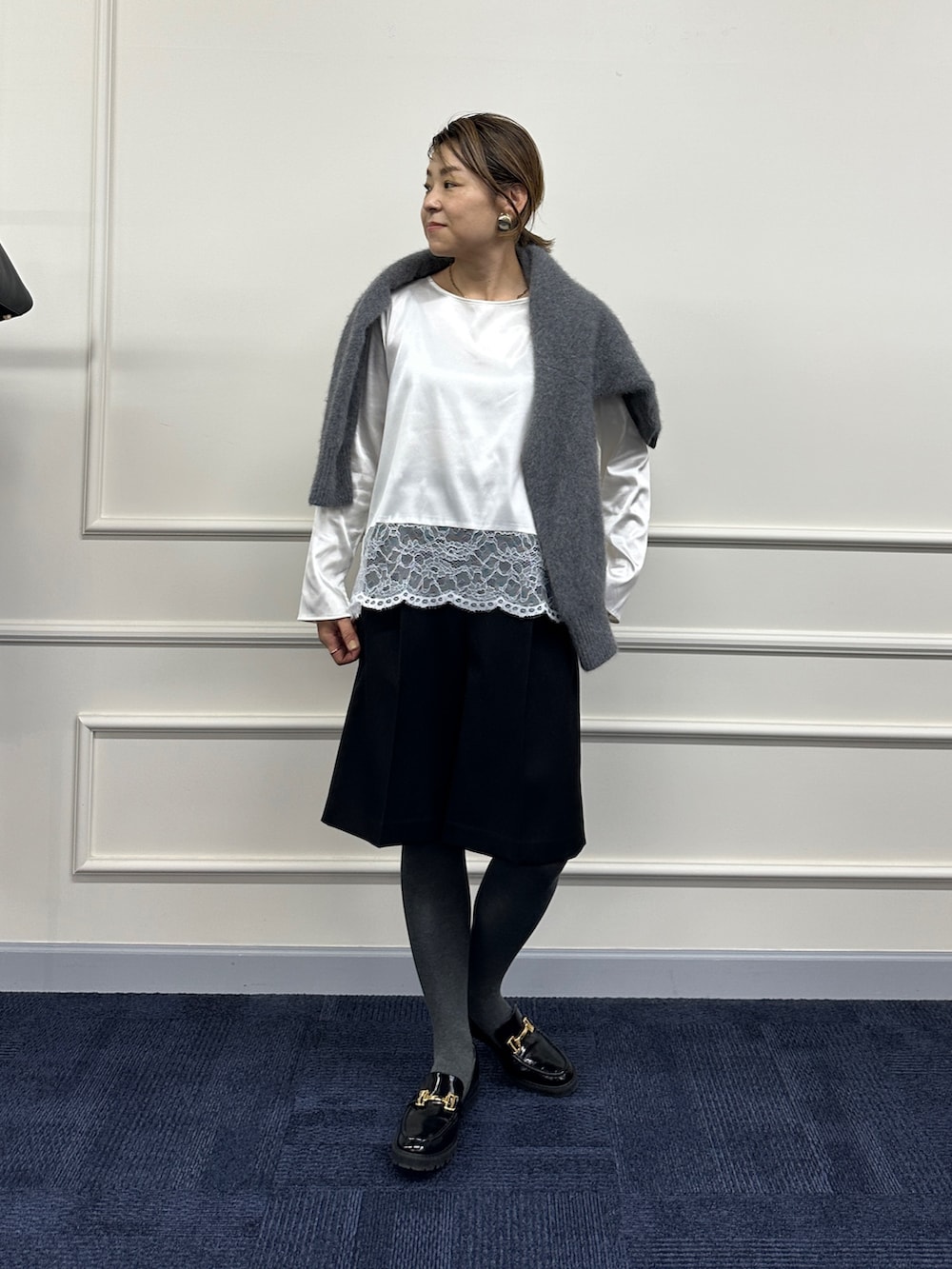 グレー系のニット/セーター、ホワイト系のシャツ/ブラウス、ブラック系のその他パンツを着用したレディースの秋コーディネートの10枚目の写真