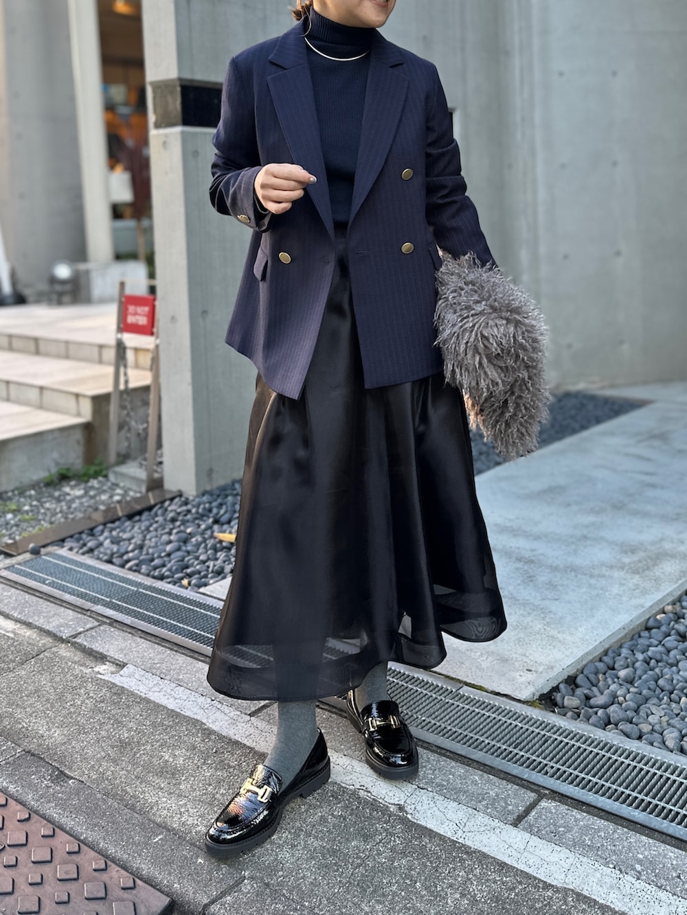 ブラック系のスカート、ブルー系のその他トップス、ブルー系のテーラードジャケットを着用したレディースの冬コーディネートの5枚目の写真