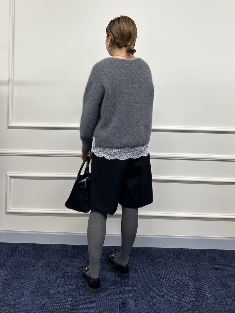 グレー系のニット/セーター、ホワイト系のシャツ/ブラウス、ブラック系のその他パンツを着用したレディースの秋コーディネートの6枚目の写真