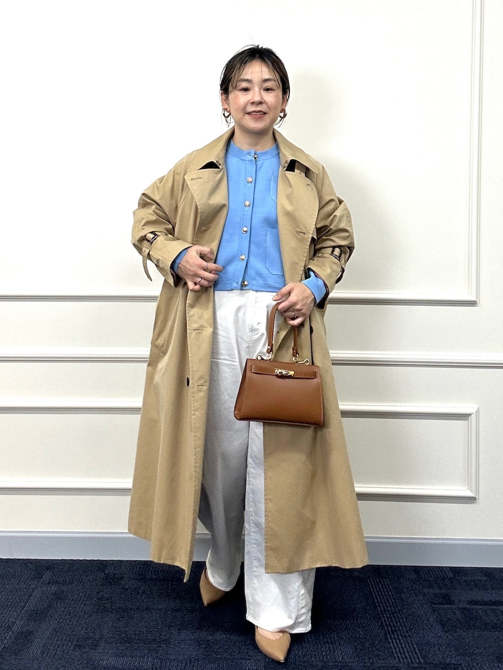 ベージュ系のトレンチコート、ブルー系のカーディガン/ボレロ、イエロー系のショルダーバッグを着用したレディースの春コーディネートの3枚目の写真