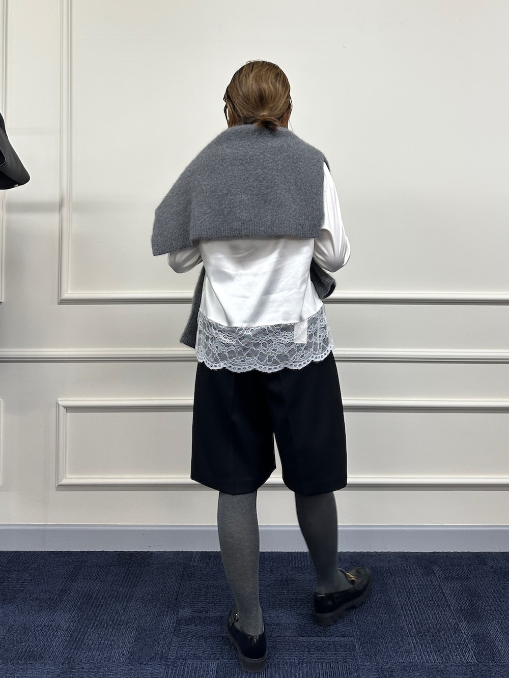 グレー系のニット/セーター、ホワイト系のシャツ/ブラウス、ブラック系のその他パンツを着用したレディースの秋コーディネートの9枚目の写真