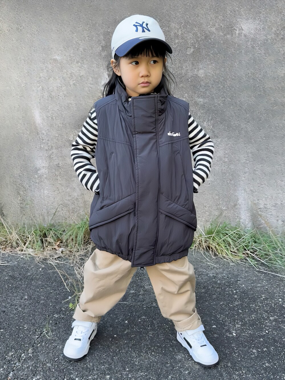 ブラック系のダウンベスト、ブラック系のトップス、ベージュ系のチノパンツを着用したキッズの冬コーディネートの4枚目の写真