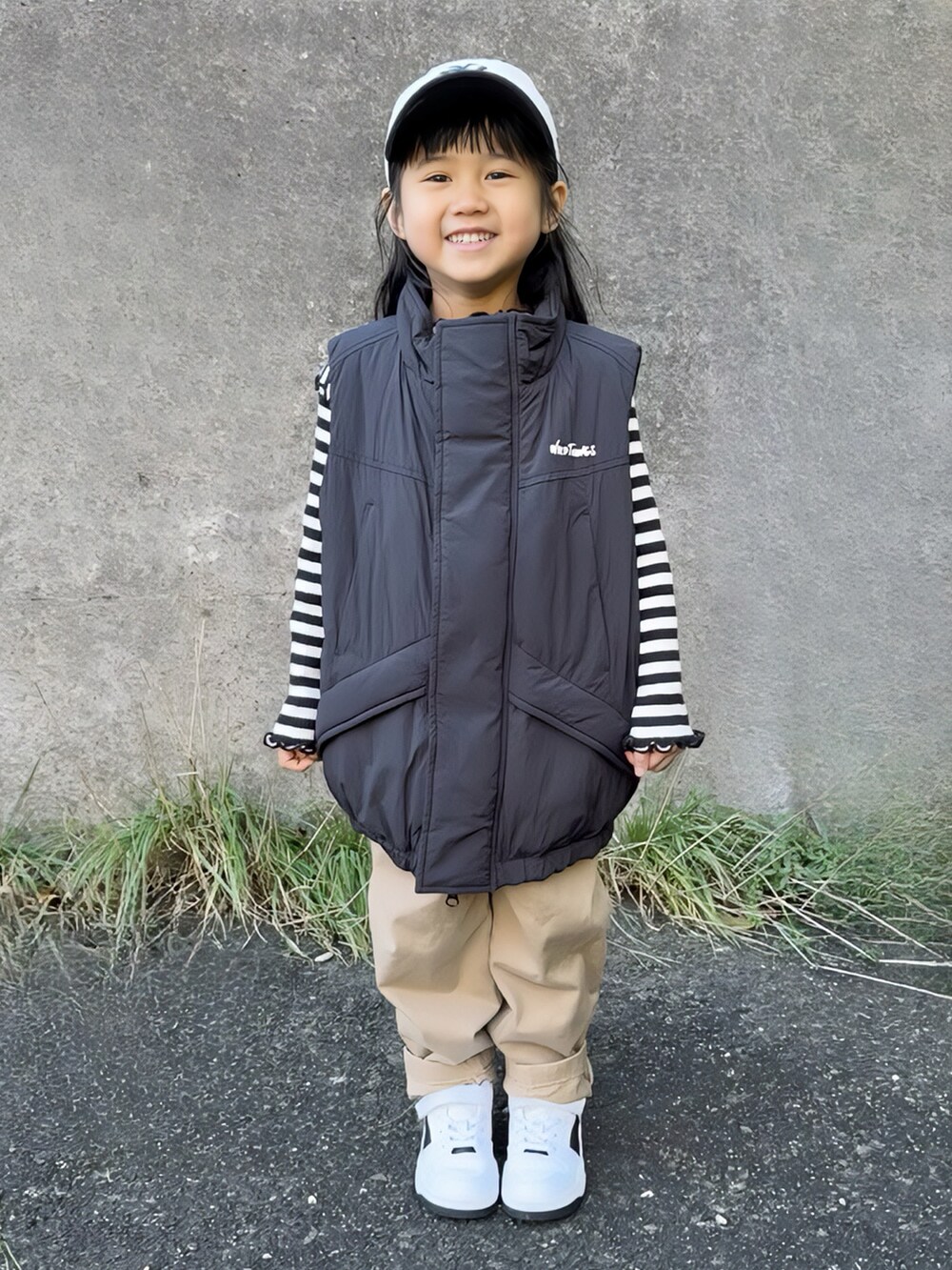 ブラック系のダウンベスト、ブラック系のトップス、ベージュ系のチノパンツを着用したキッズの冬コーディネートの5枚目の写真