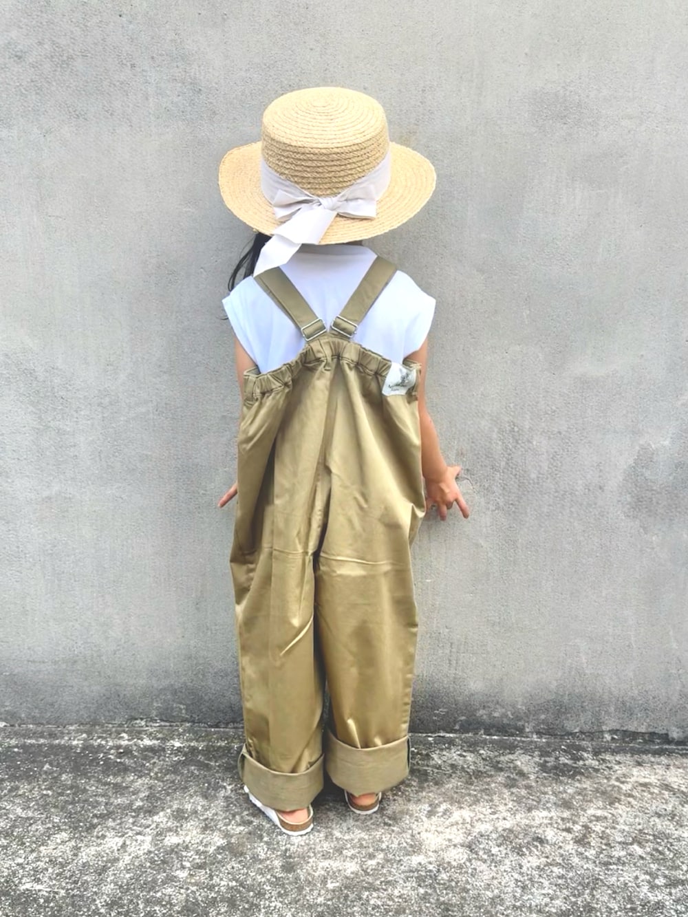 ベージュ系のサロペット/オーバーオール、ホワイト系のサンダル、ベージュ系のハットを着用したキッズの夏コーディネートの4枚目の写真