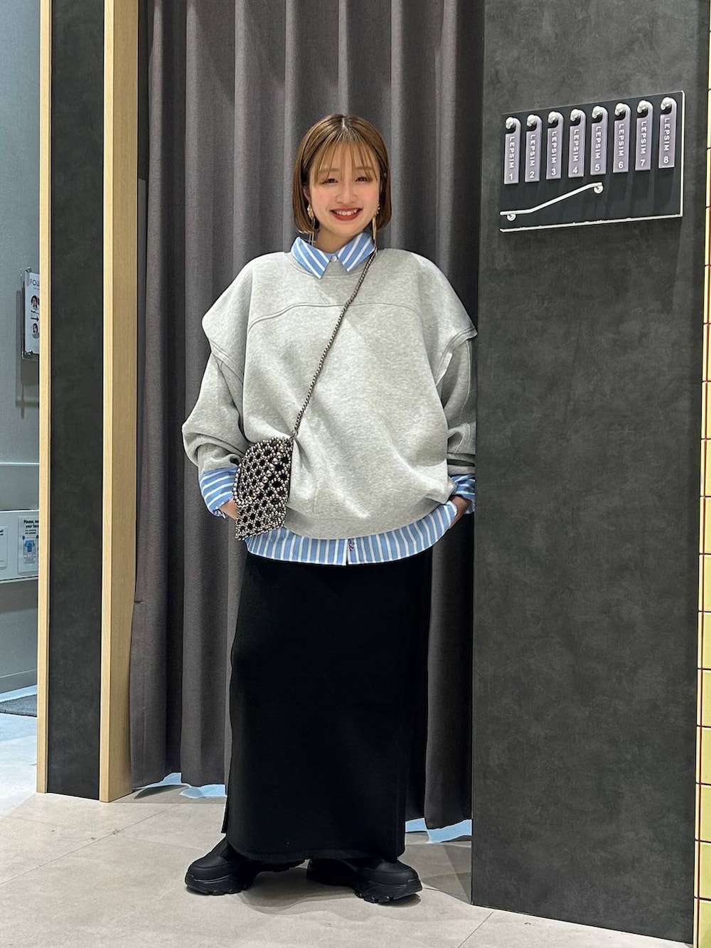 ブラック系のスカート、グレー系のスウェット、ブラック系のスニーカーを着用したレディースの秋コーディネートの2枚目の写真