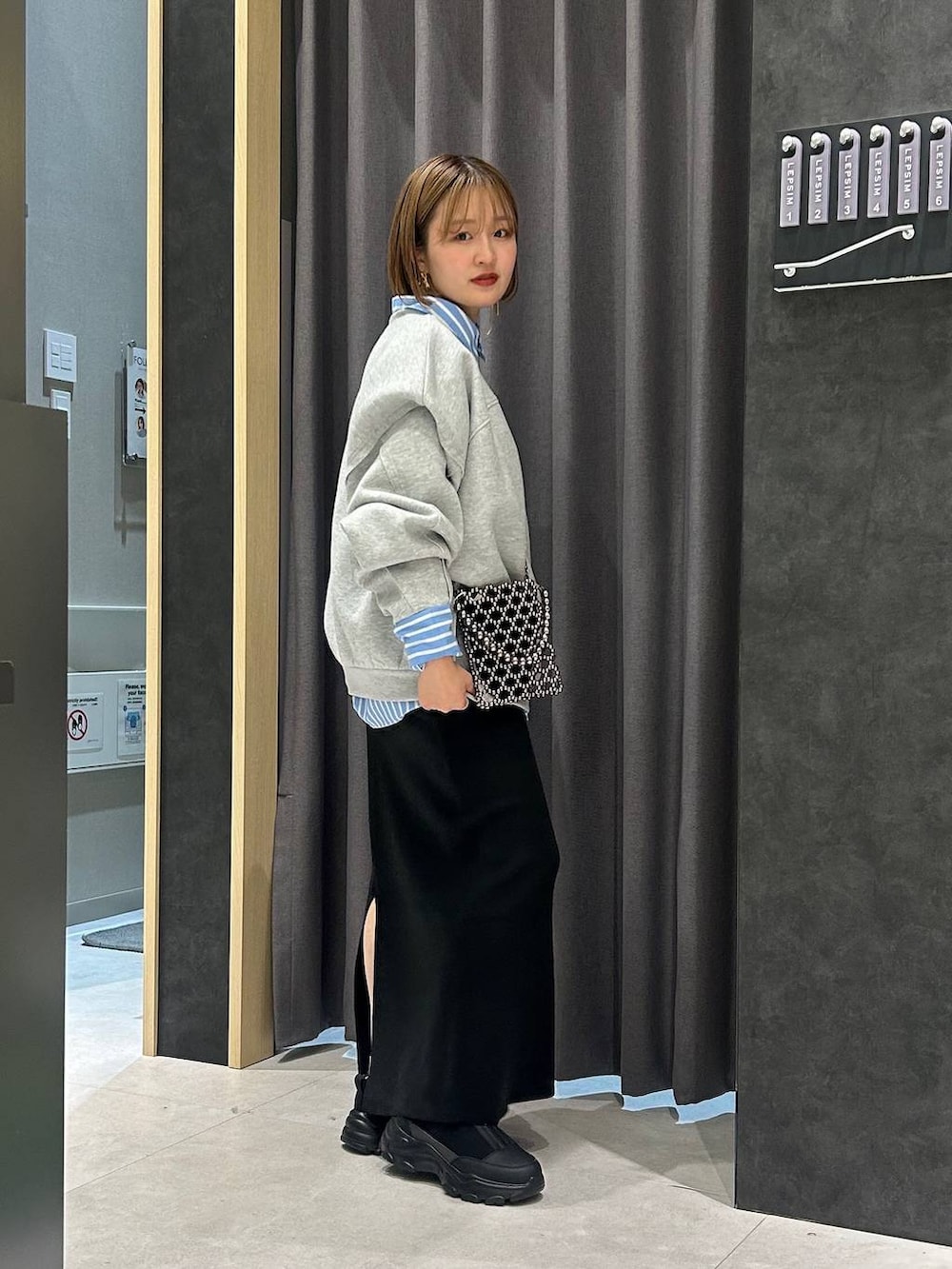 ブラック系のスカート、グレー系のスウェット、ブラック系のスニーカーを着用したレディースの秋コーディネートの3枚目の写真