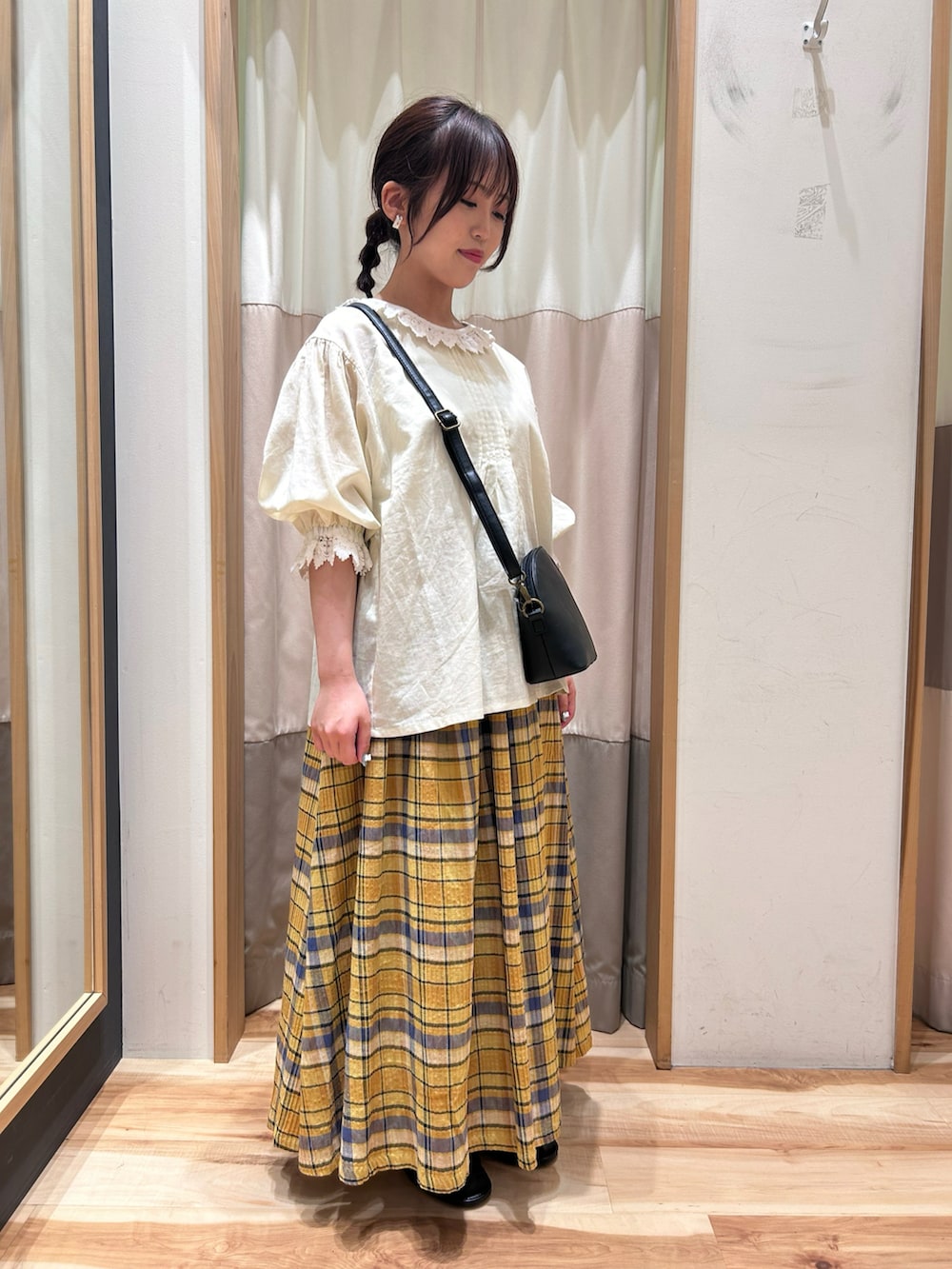 イエロー系のスカート、ホワイト系のシャツ/ブラウス、ブラック系のハンドバッグを着用したレディースの春コーディネートの2枚目の写真