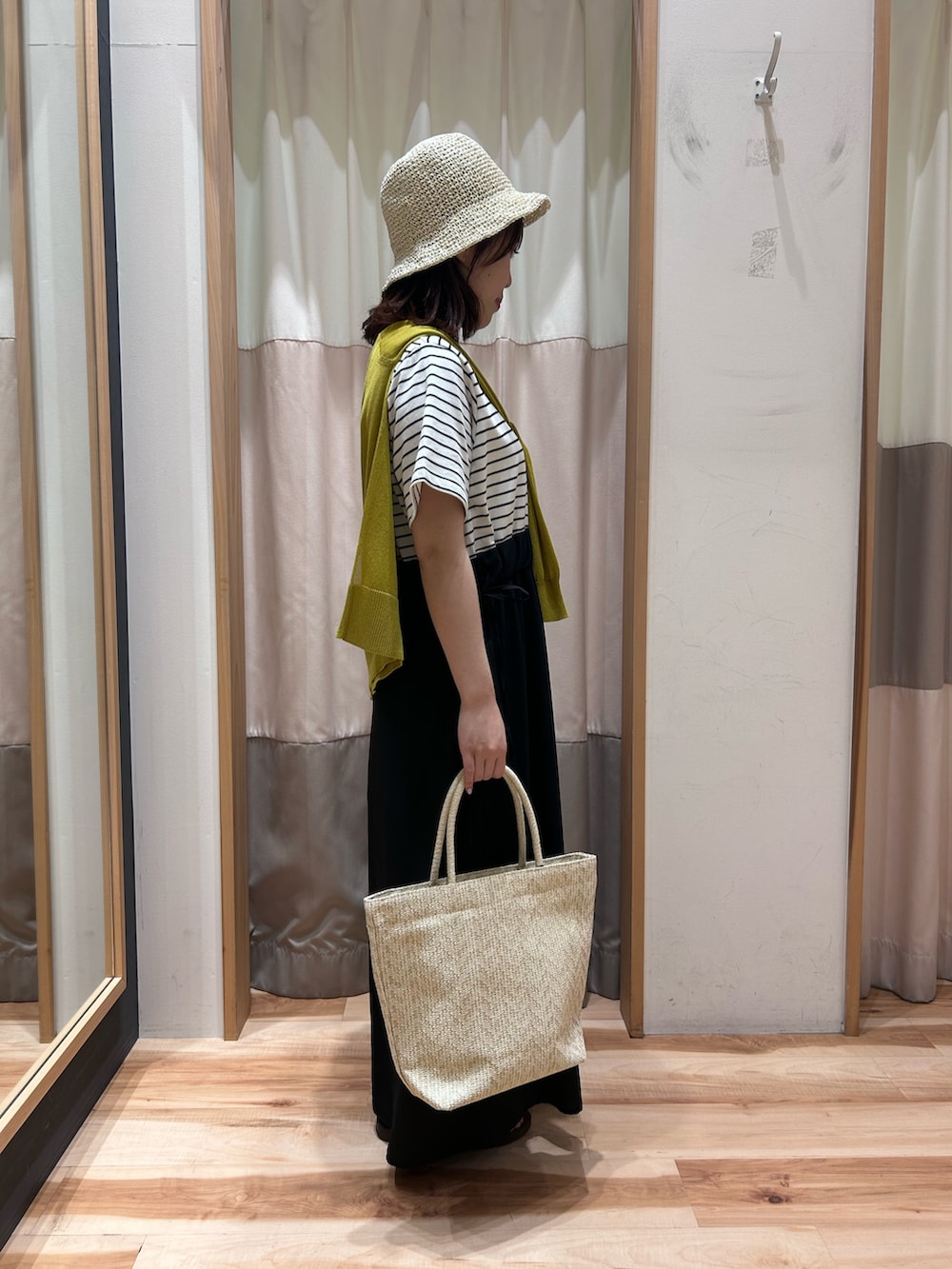 ホワイト系のハンドバッグ、ホワイト系のワンピース、イエロー系のカーディガン/ボレロを着用したレディースの夏コーディネートの3枚目の写真