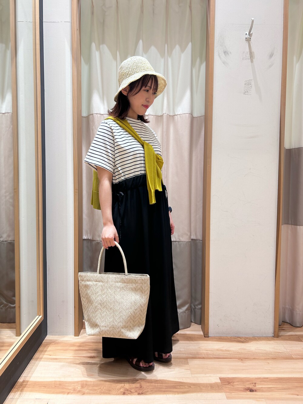 ホワイト系のハンドバッグ、ホワイト系のワンピース、イエロー系のカーディガン/ボレロを着用したレディースの夏コーディネートの2枚目の写真