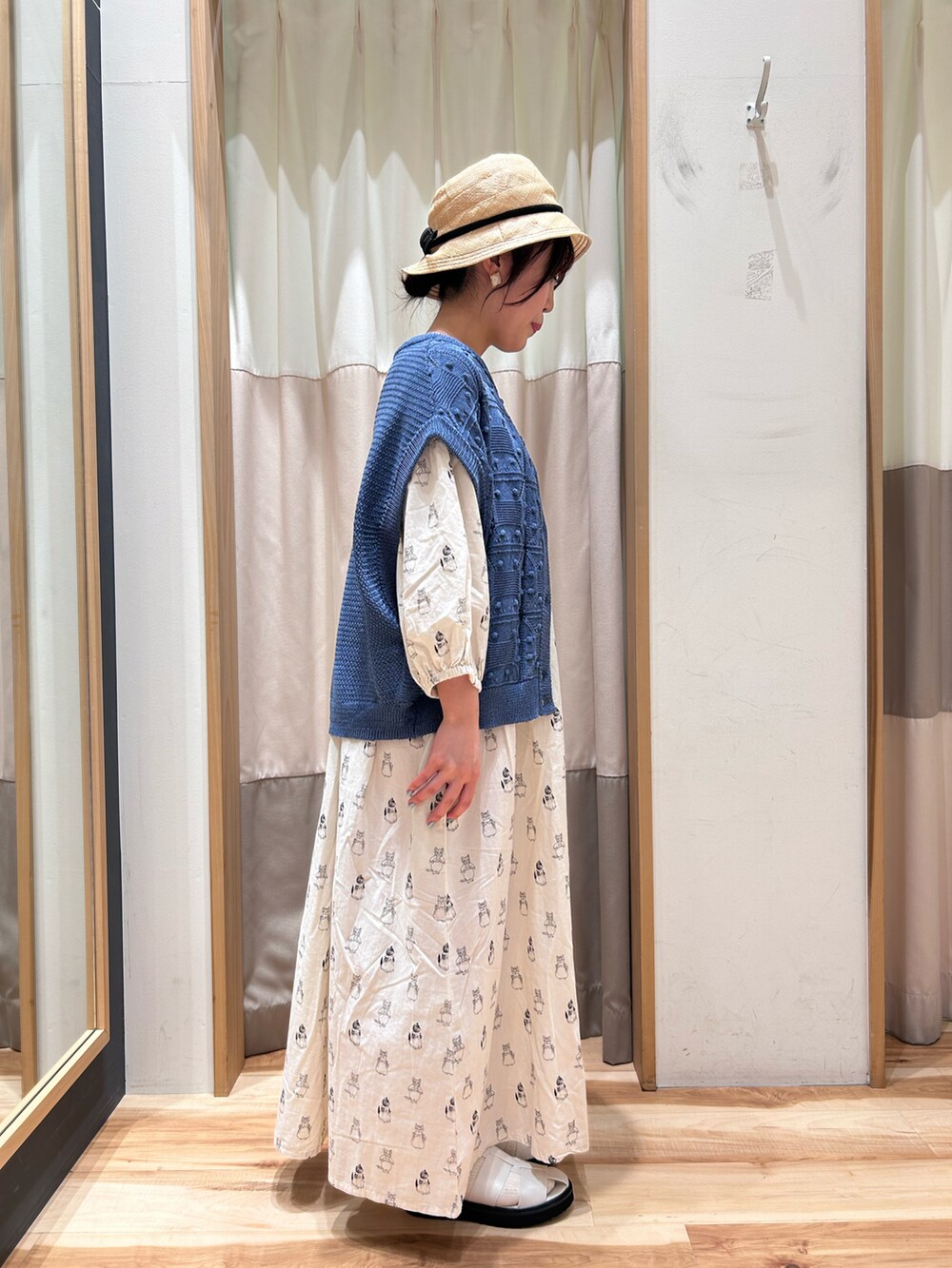 ホワイト系のワンピース、ブルー系のベスト、ホワイト系のサンダルを着用したレディースの春コーディネートの2枚目の写真