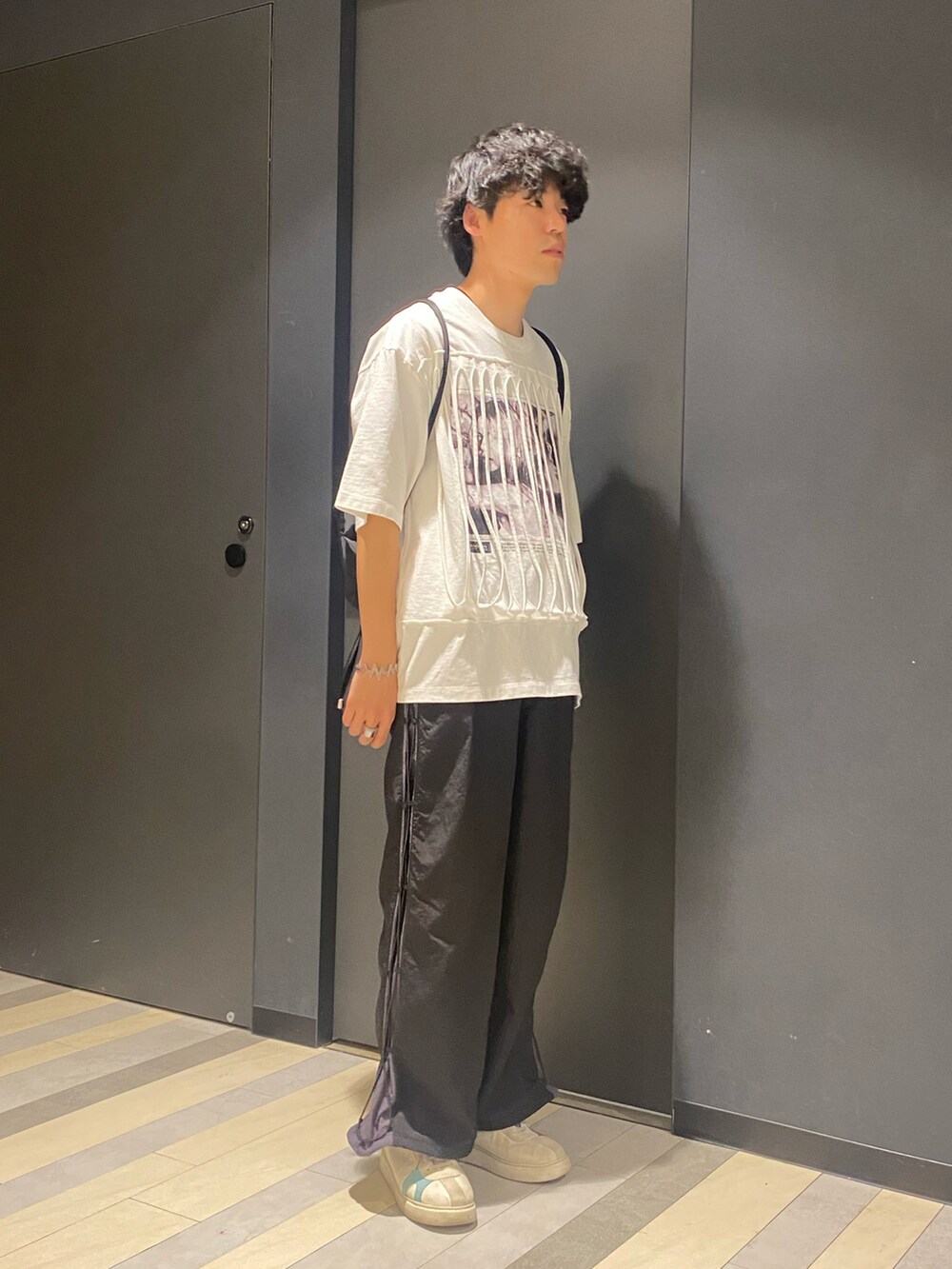 ホワイト系のTシャツ/カットソー、ブラック系のその他パンツ、ブラック系のバックパック/リュックを着用したメンズの春コーディネートの2枚目の写真