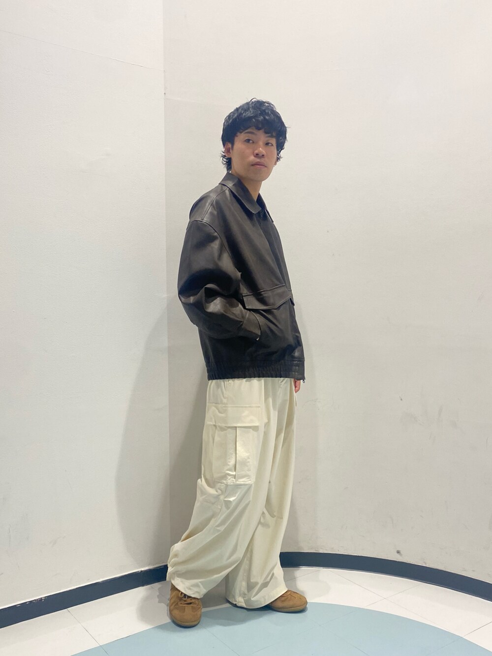 ブラウン系のブルゾン、ホワイト系のカーゴパンツ、ブラウン系のスニーカーを着用したメンズの夏コーディネートの2枚目の写真