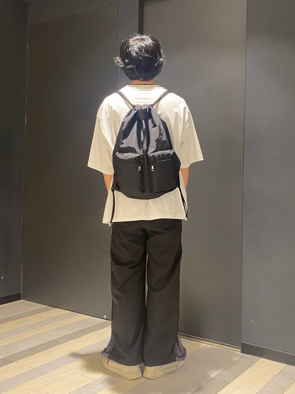 ホワイト系のTシャツ/カットソー、ブラック系のその他パンツ、ブラック系のバックパック/リュックを着用したメンズの春コーディネートの3枚目の写真