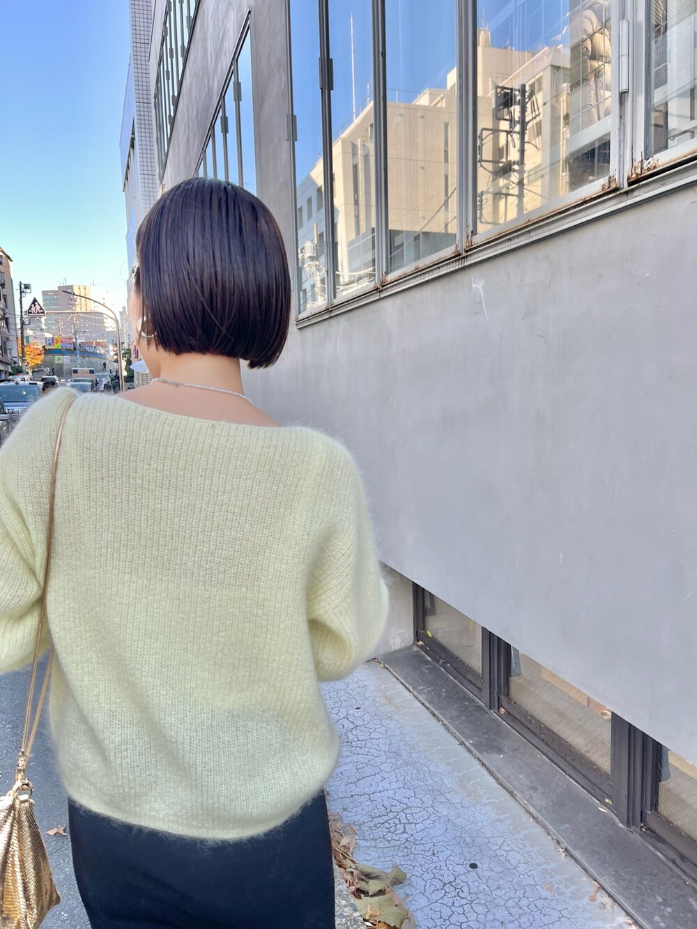 ゴールド系のクラッチバッグ、イエロー系のニット/セーター、ブラック系のスカートを着用したレディースの冬コーディネートの4枚目の写真