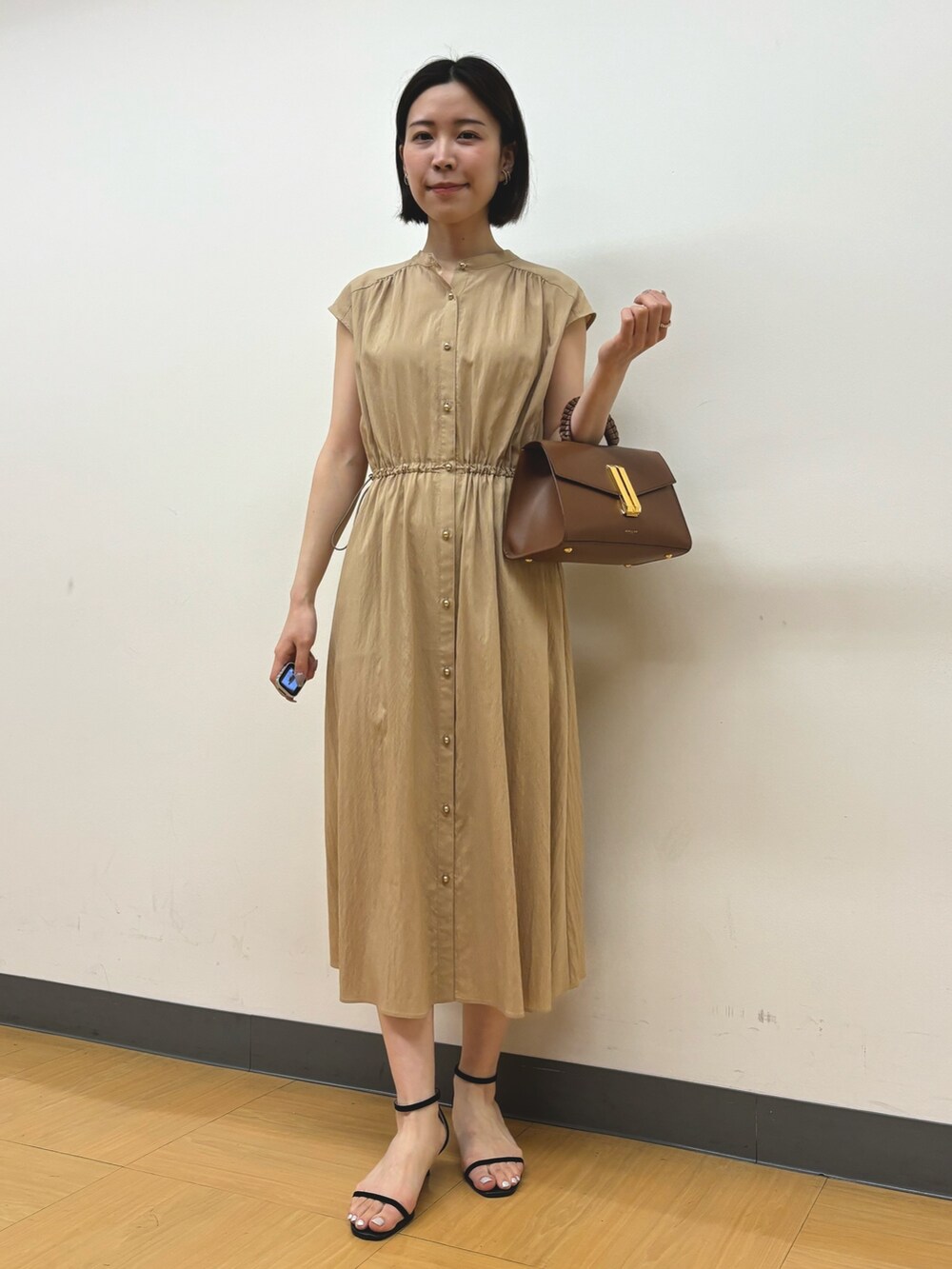 イエロー系のワンピース、ゴールド系のイヤリングを着用したレディースの春コーディネートの3枚目の写真