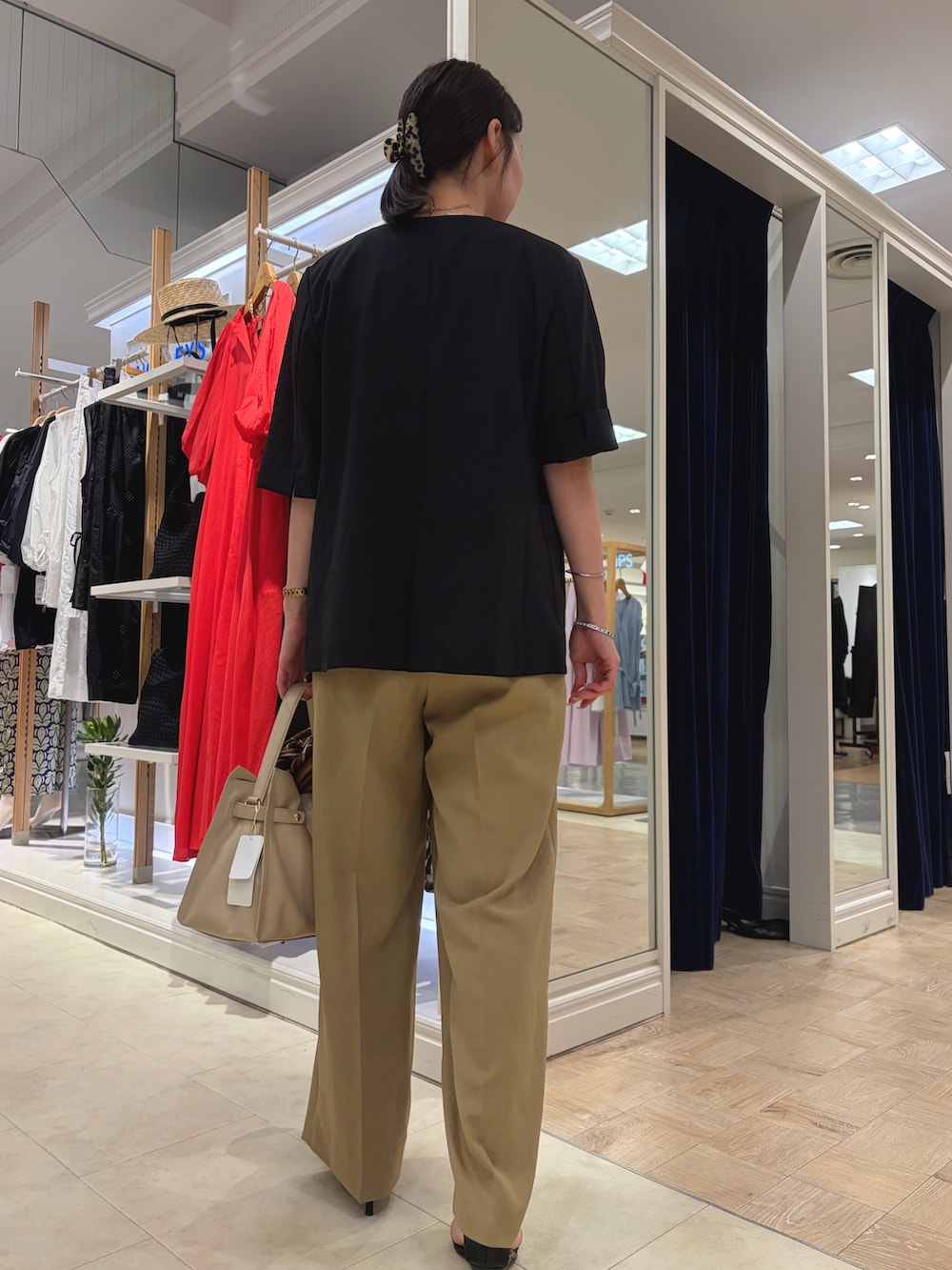 ベージュ系のトートバッグ、ブラック系のノーカラージャケット、ホワイト系のTシャツ/カットソーを着用したレディースの夏コーディネートの4枚目の写真