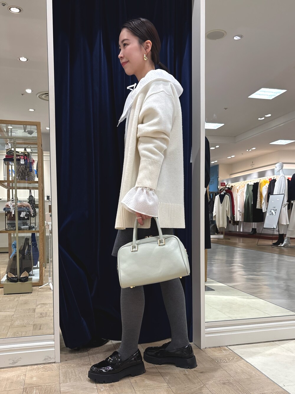 グレー系のスカート、グリーン系のショルダーバッグ、ホワイト系のカーディガン/ボレロを着用したレディースの冬コーディネートの3枚目の写真
