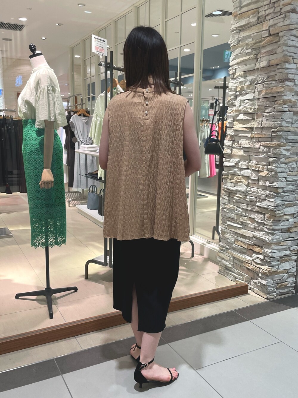 イエロー系のシャツ/ブラウス、ブラック系のスカート、ホワイト系のハンドバッグを着用したレディースの春コーディネートの7枚目の写真