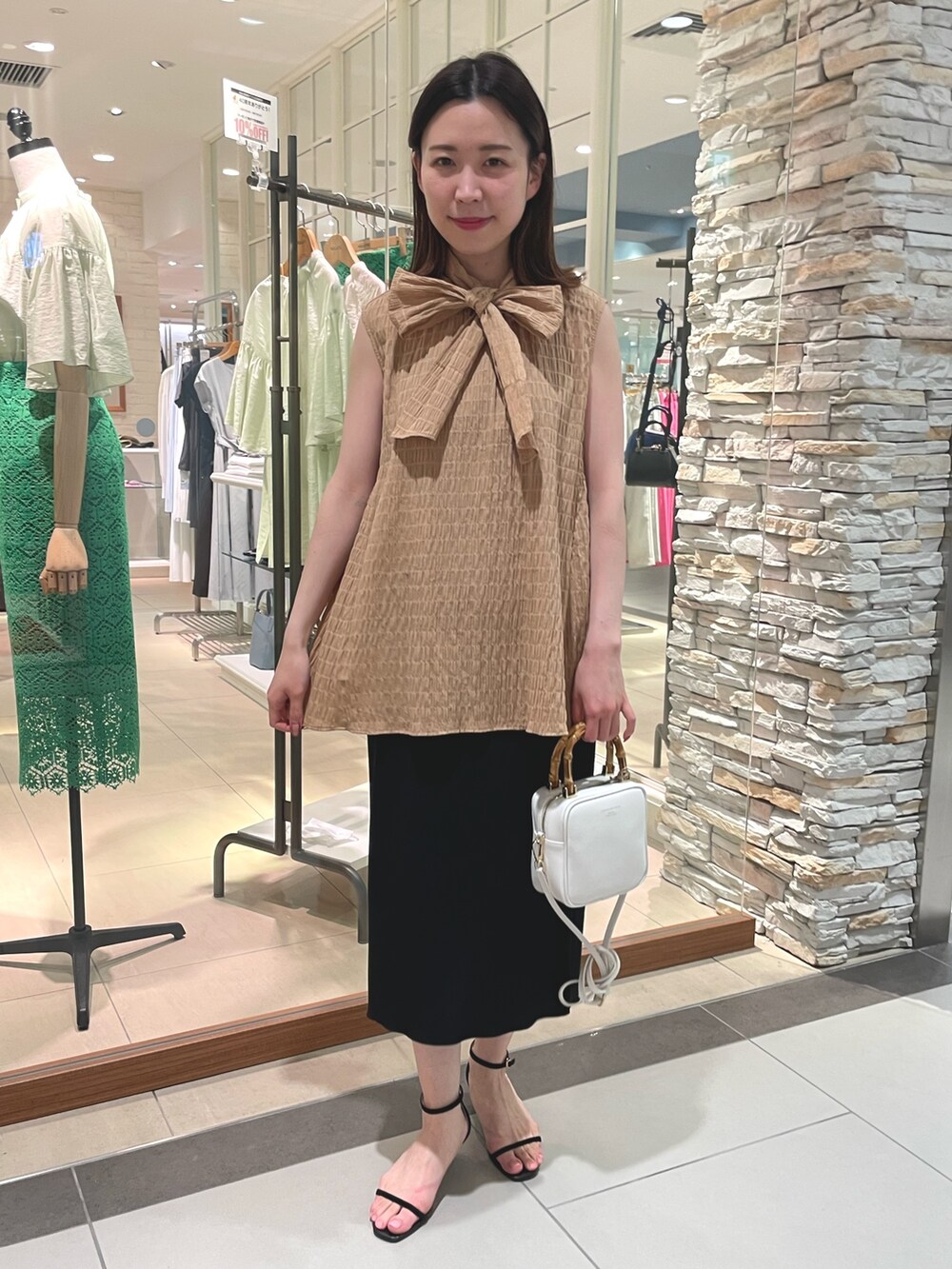 イエロー系のシャツ/ブラウス、ブラック系のスカート、ホワイト系のハンドバッグを着用したレディースの春コーディネートの2枚目の写真