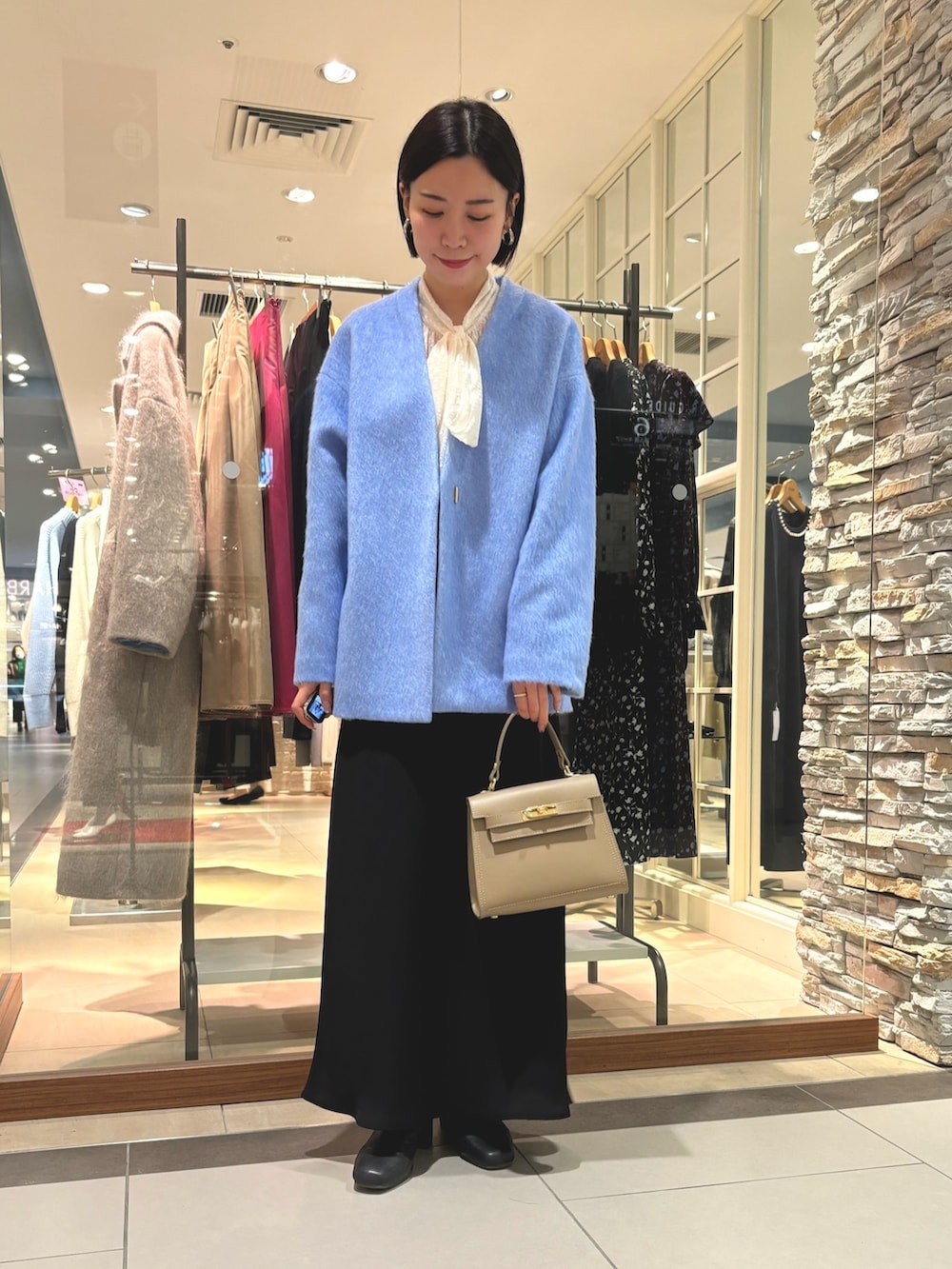 ブラック系のスカート、ベージュ系のショルダーバッグ、ブルー系のその他アウターを着用したレディースの冬コーディネートの3枚目の写真