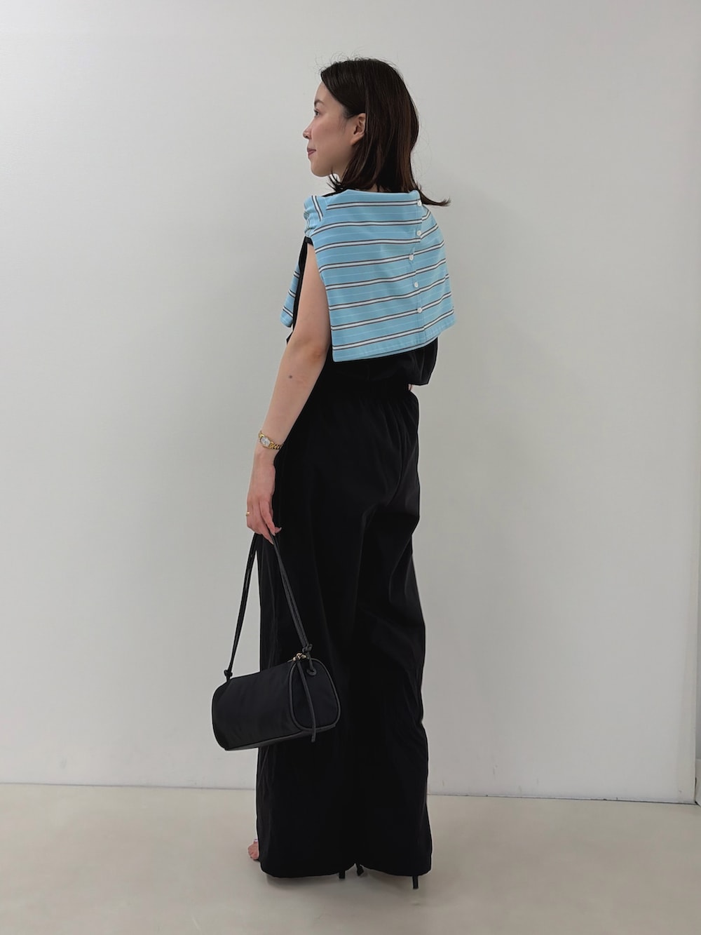ブラック系のつなぎ/オールインワン、ブルー系のカーディガン/ボレロ、ブラック系のショルダーバッグを着用したレディースの夏コーディネートの5枚目の写真