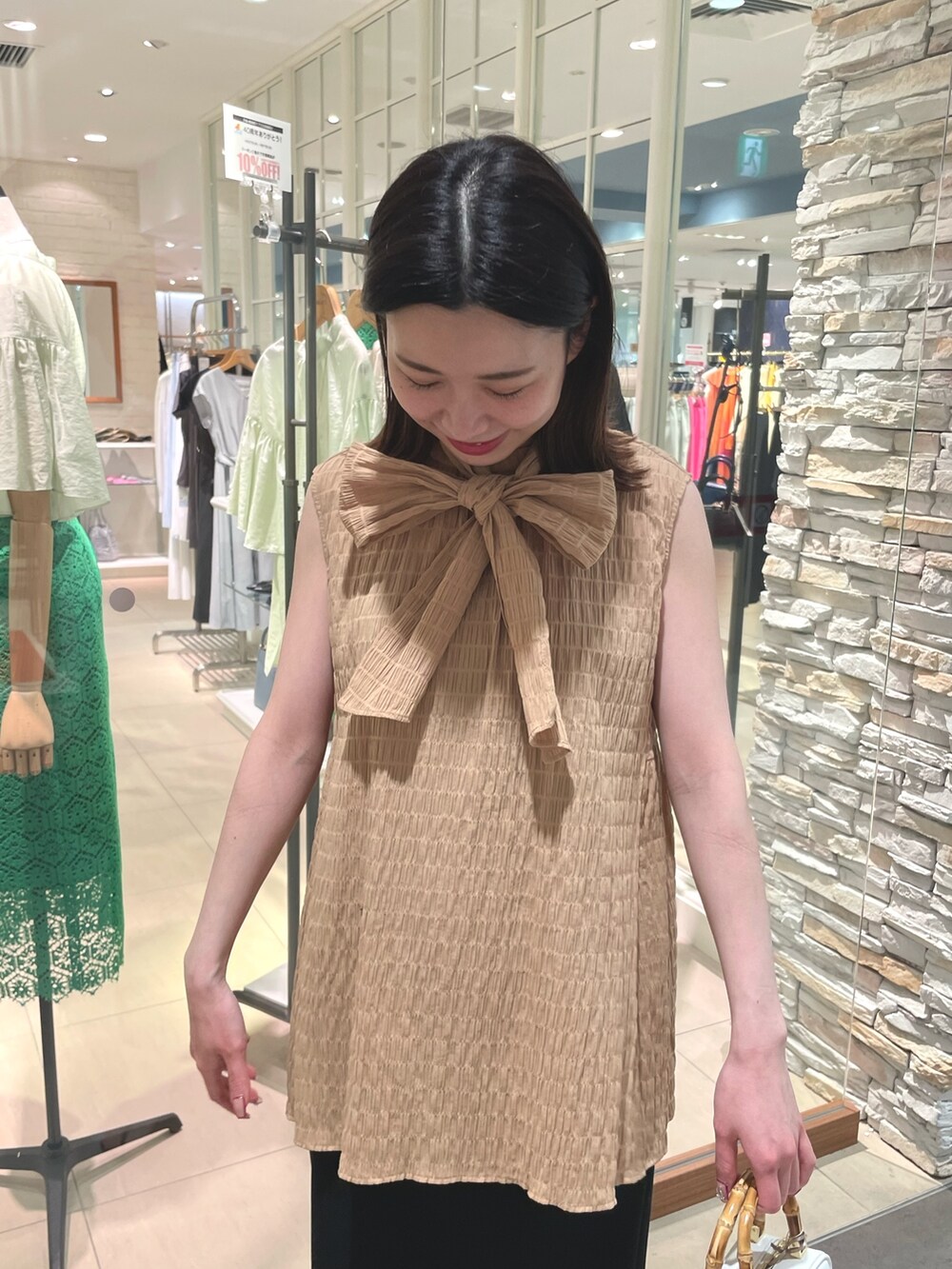 イエロー系のシャツ/ブラウス、ブラック系のスカート、ホワイト系のハンドバッグを着用したレディースの春コーディネートの4枚目の写真