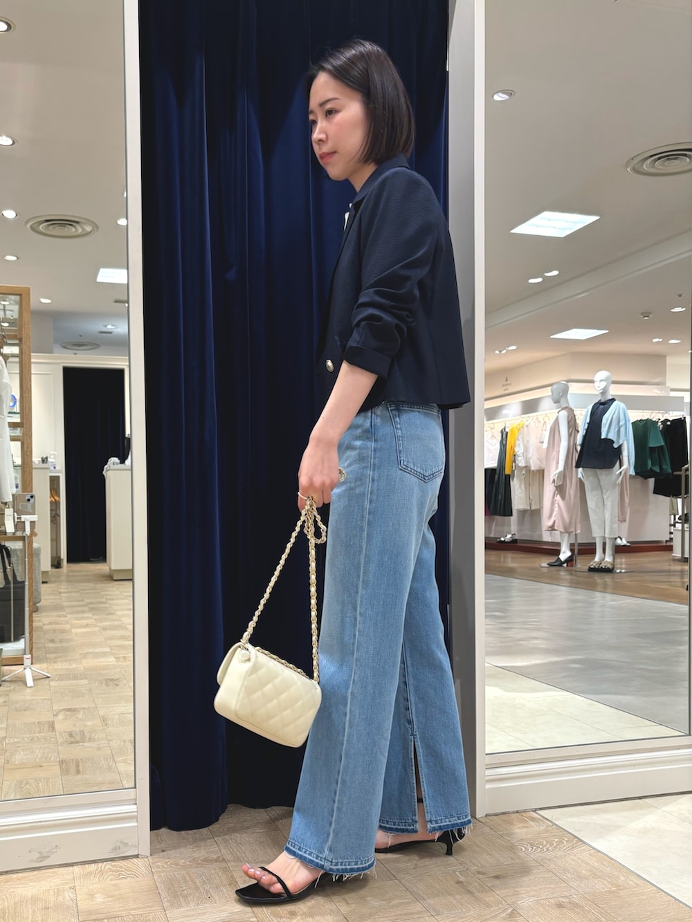 ブルー系のデニムパンツ、ホワイト系のショルダーバッグ、ブルー系のテーラードジャケットを着用したレディースの春コーディネートの3枚目の写真