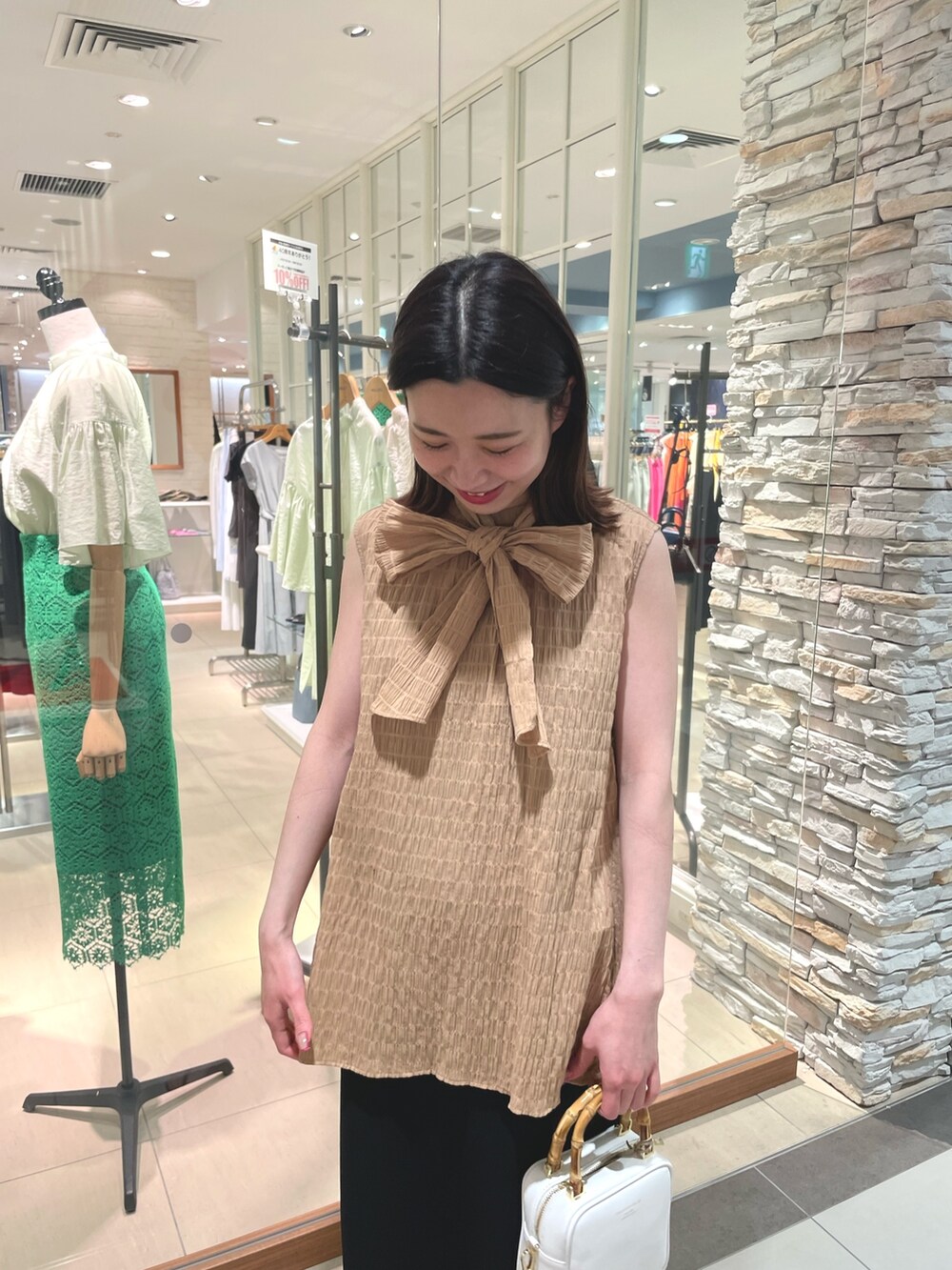 イエロー系のシャツ/ブラウス、ブラック系のスカート、ホワイト系のハンドバッグを着用したレディースの春コーディネートの5枚目の写真