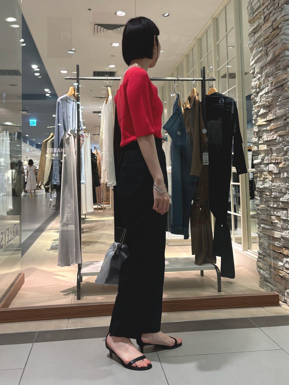 ブラック系のその他パンツ、シルバー系のショルダーバッグ、レッド系のニット/セーターを着用したレディースの夏コーディネートの5枚目の写真
