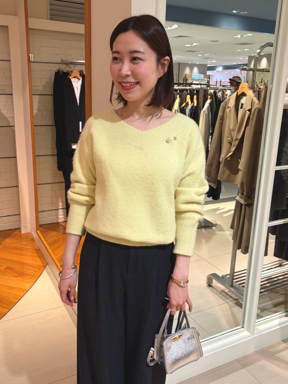 イエロー系のニット/セーター、ブラック系のその他パンツ、シルバー系のショルダーバッグを着用したレディースの冬コーディネートの7枚目の写真