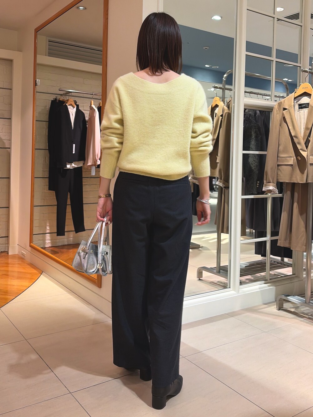 イエロー系のニット/セーター、ブラック系のその他パンツ、シルバー系のショルダーバッグを着用したレディースの冬コーディネートの4枚目の写真