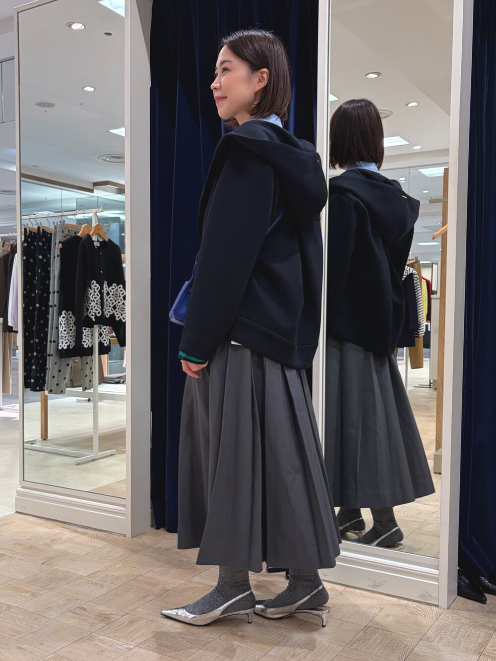 ホワイト系のカーディガン/ボレロ、ブルー系のシャツ/ブラウス、グレー系のスカートを着用したレディースの秋コーディネートの3枚目の写真