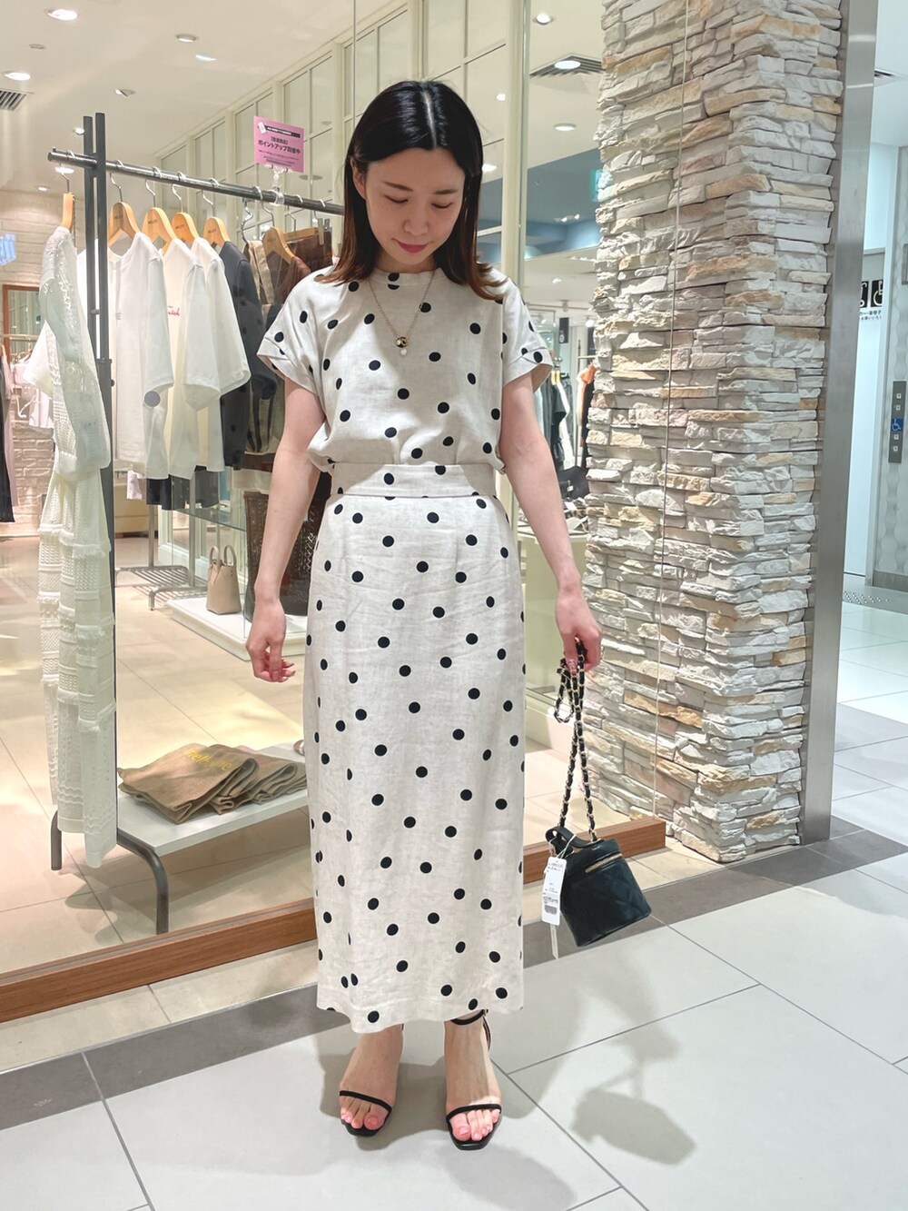 ブラック系のサンダル、ベージュ系のスカート、ブラック系のシャツ/ブラウスを着用したレディースの夏コーディネートの2枚目の写真