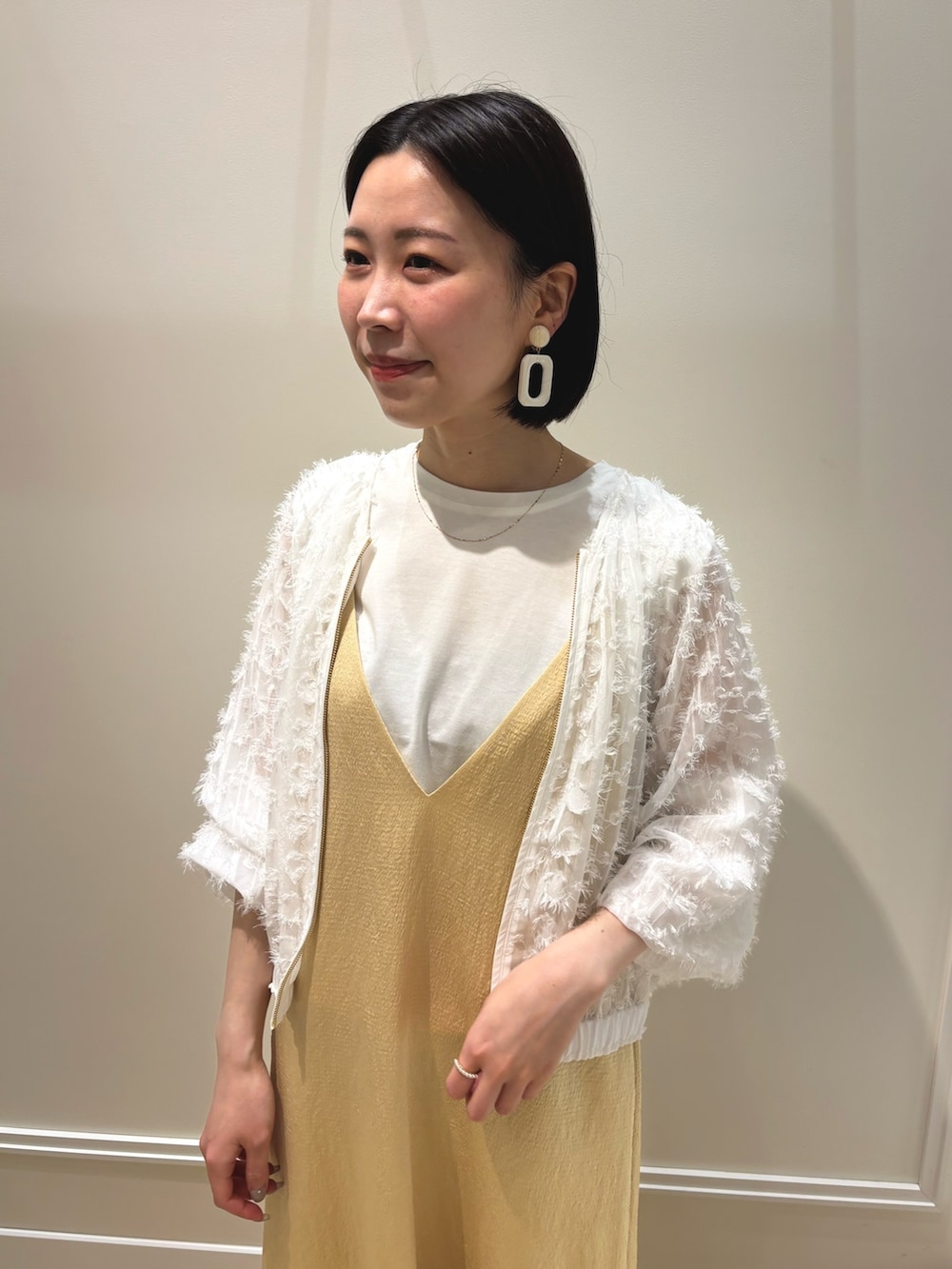 イエロー系のワンピース、ホワイト系のブルゾン、ホワイト系のTシャツ/カットソーを着用したレディースの夏コーディネートの6枚目の写真