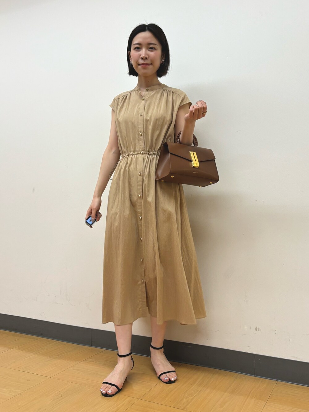 イエロー系のワンピース、ゴールド系のイヤリングを着用したレディースの春コーディネートの2枚目の写真