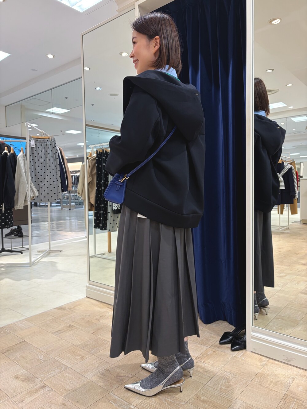 ホワイト系のカーディガン/ボレロ、ブルー系のシャツ/ブラウス、グレー系のスカートを着用したレディースの秋コーディネートの4枚目の写真